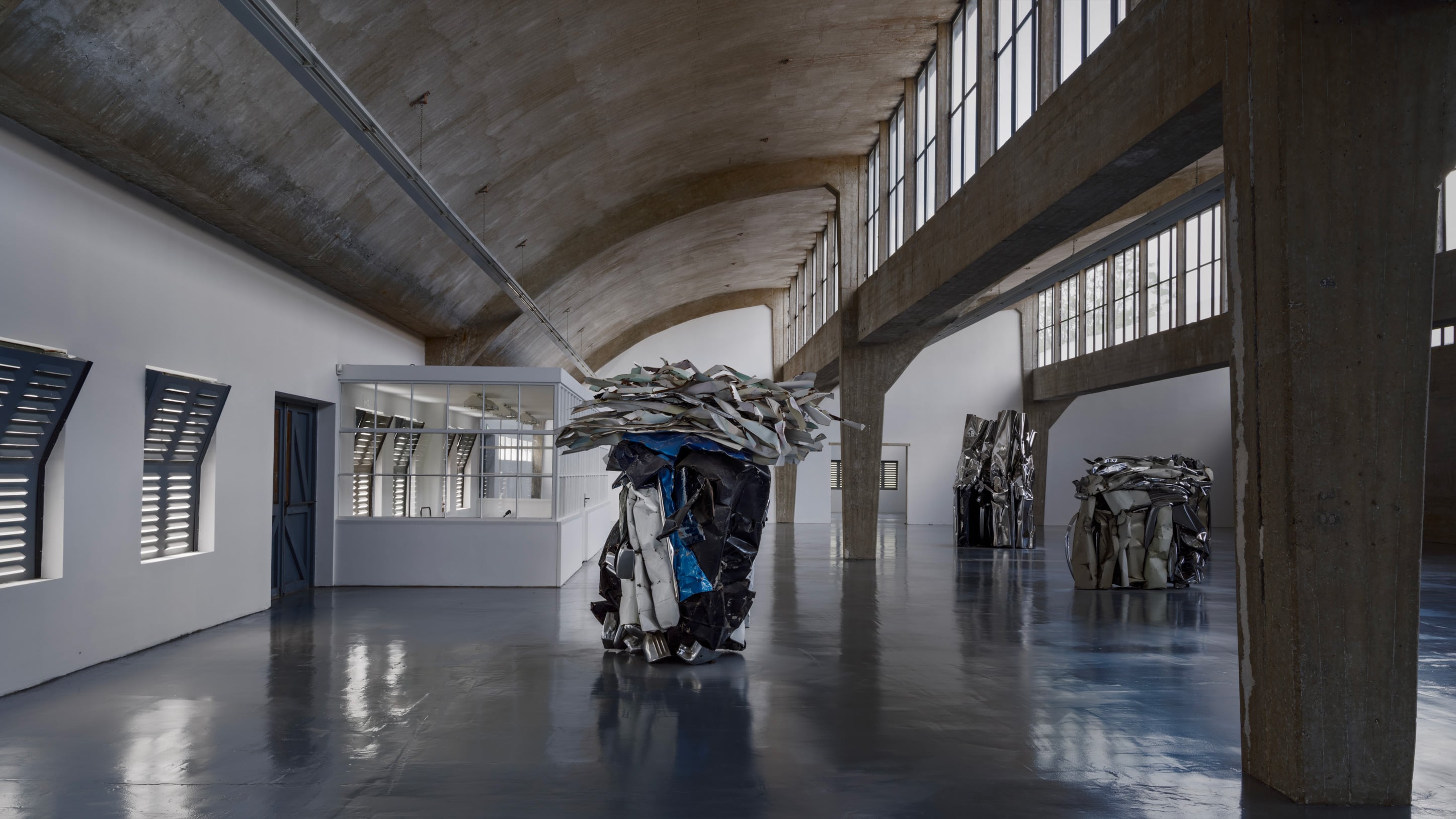 ZAMU Amsterdam sculpture by American sculptor John Chamberlain: art of assemblage, scrap metal, plated and crushed metal, silver and blue colors, industrial concrete building, polished floor